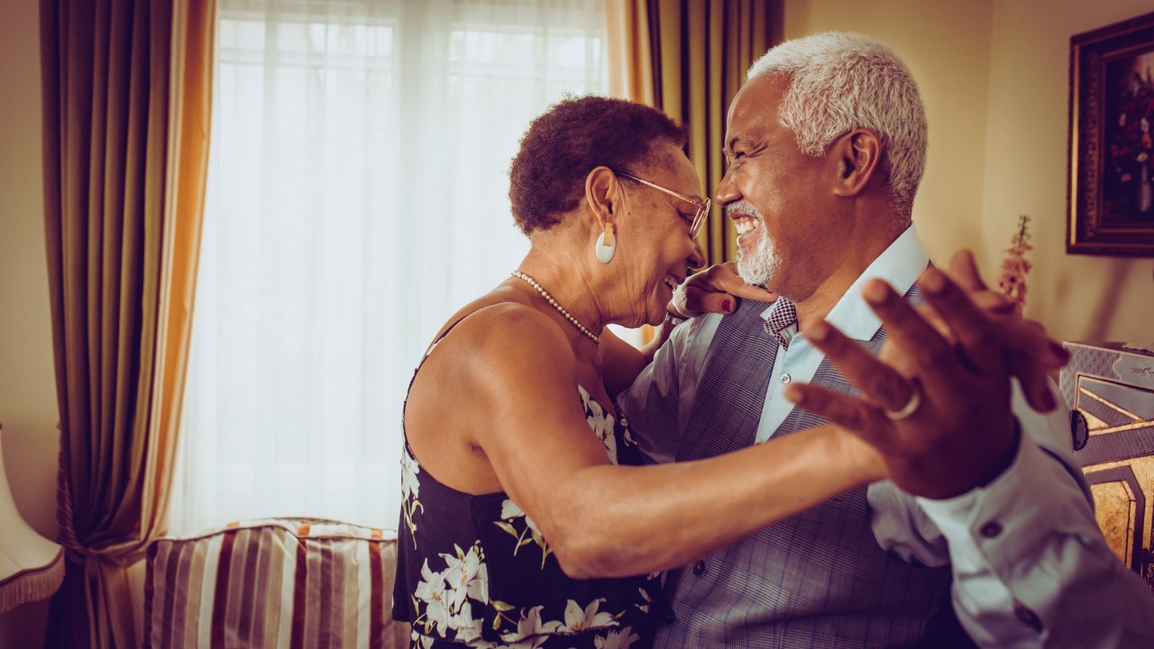 A joyful senior couple dancing together at home